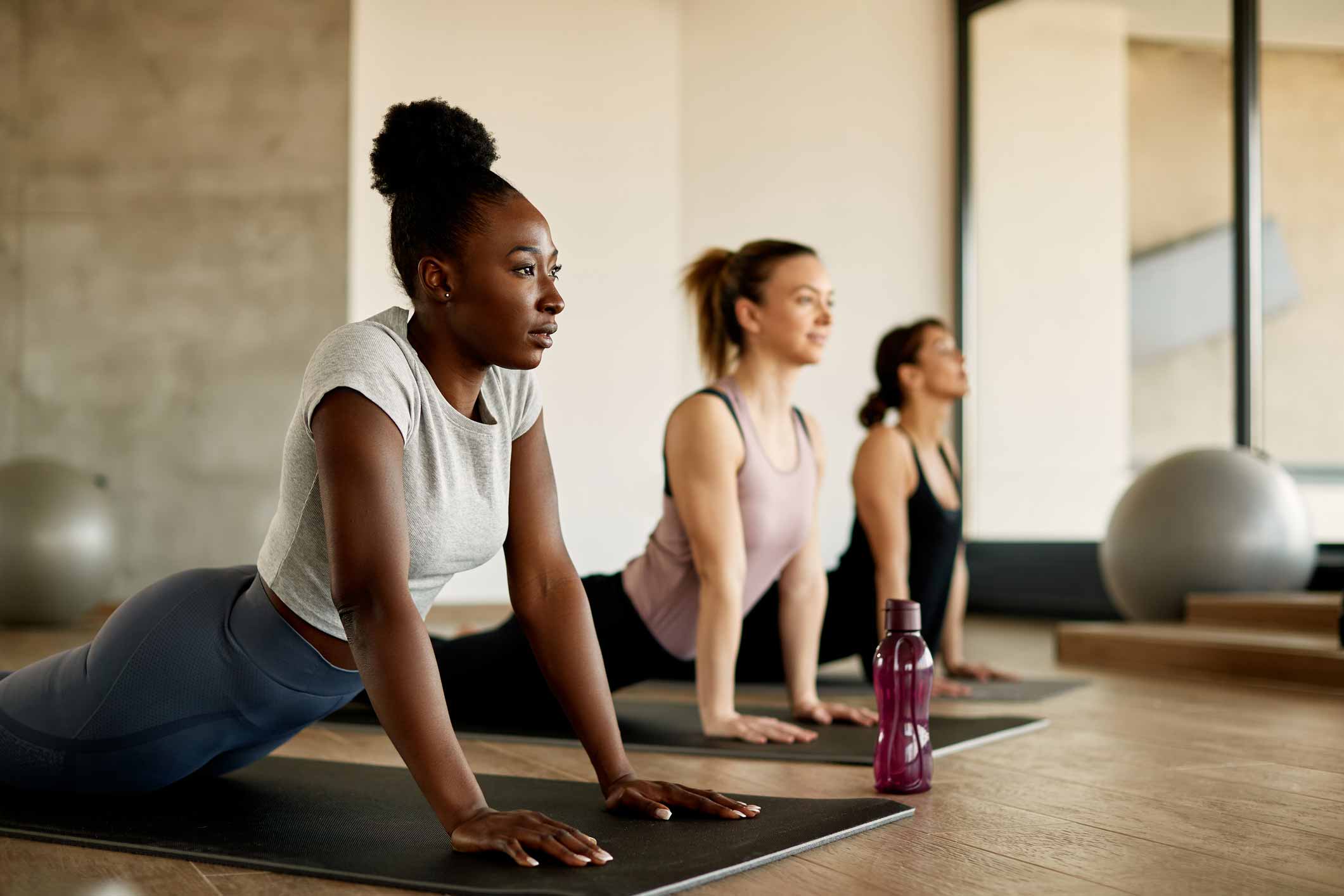 Drei Frauen beim Fitness-Yoga auf ihrer Matte im Wellnessbereich des Hotels und Spas in der Drôme Provençale Château Les Oliviers de Salettes.