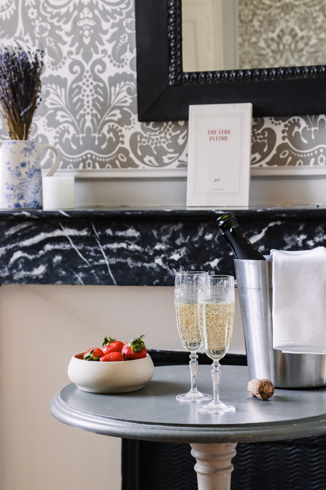 Two glasses of champagne and a bowl of strawberries on a pedestal table at Château Les Oliviers de Salettes