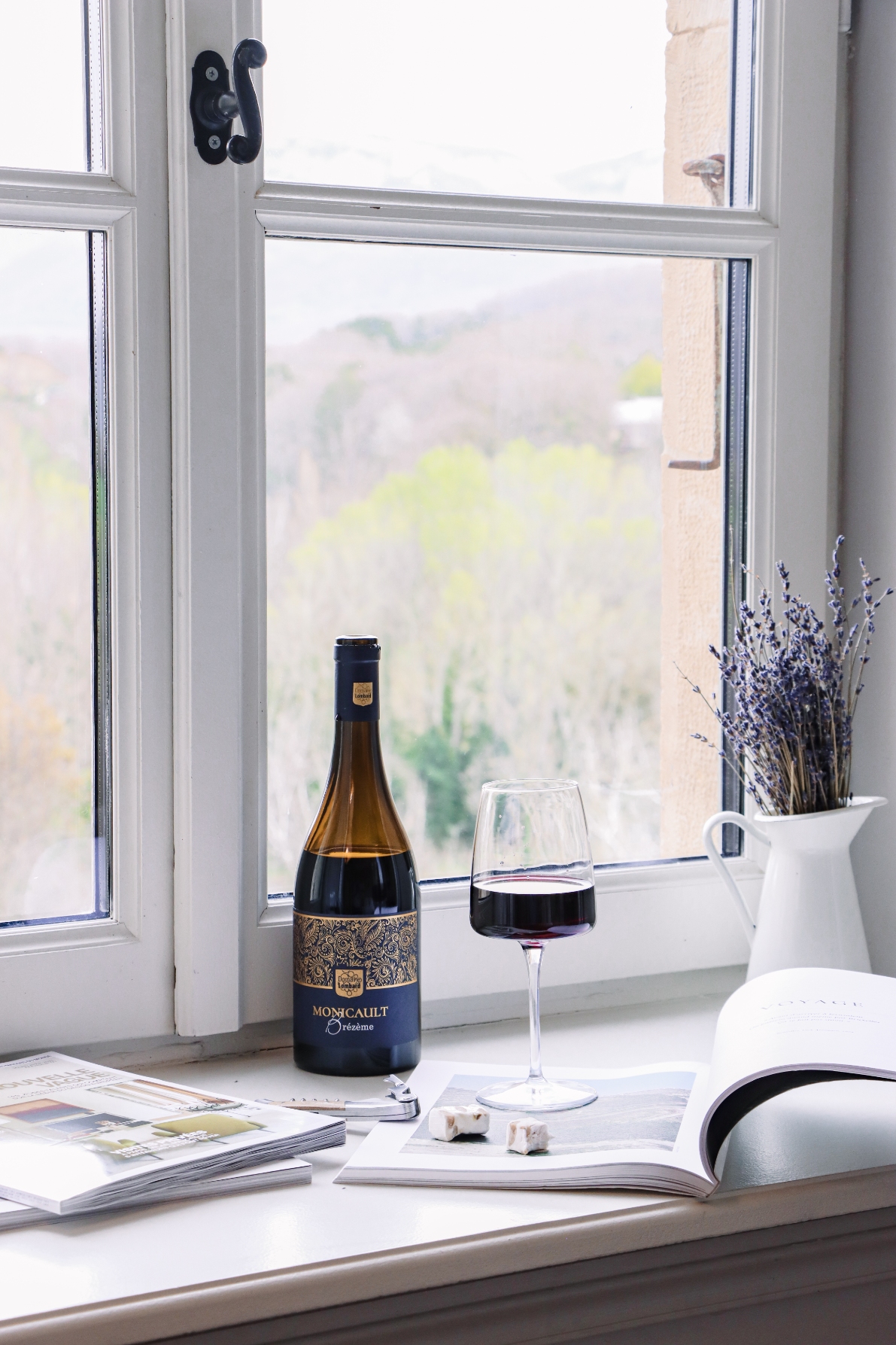 Magazine, verre de vin et bouquet de lavande posés au bord d'une fenêtre du Château Les Oliviers de Salettes, hôtel, restaurant et spa à Charols